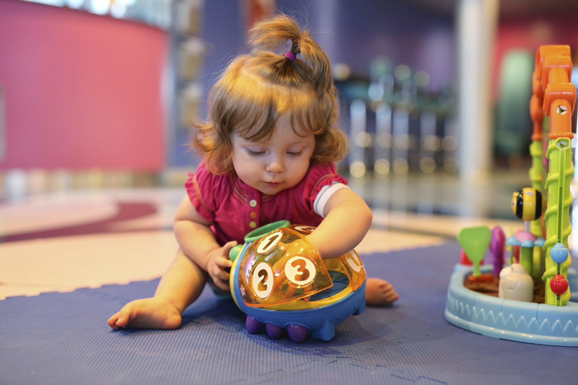 Baby girl playing with toys in a playroom of cruise liner