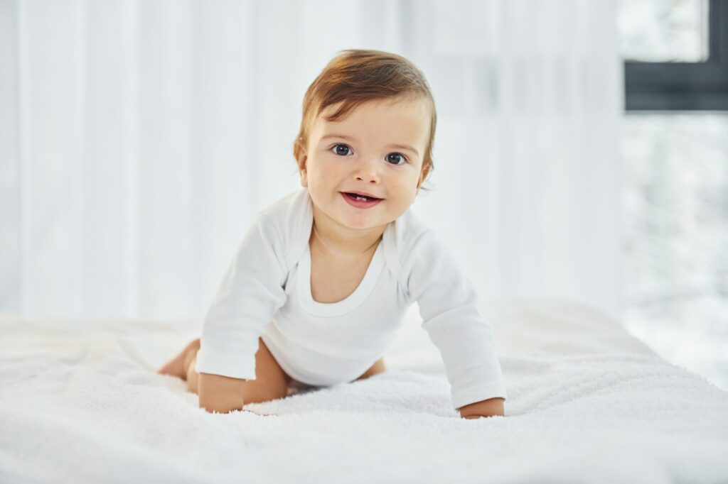 Playing on the bed. Cute little baby is indoors in the domestic room